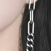 Close-up on a large hanging chain stud earrings in stainless steel on a womans ear with dark brown hair in the background