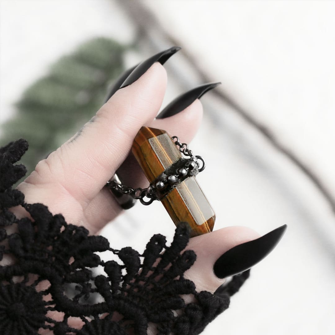 zaria-tiger-eye-choker-crystal-necklace-hellaholics (1) Zaria Dark Tiger Eye Choker hold in hand with black ong nails