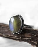 Spellbinding oval Sterling Silver Labradorite ring in blue and green colours on wooden branch