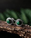 round sterling silver malachite earrings on brown branch with green background