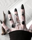 Hand with long black nails, occult finger tattoos, and many sterling silver rings, in the middle a large snake ring - the mother of sepent ring, sourunded by black onyx silver rings