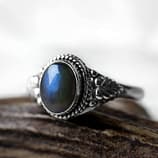 Spellbinding oval Sterling Silver Labradorite ring with intricate leaf details, in blue and green colours on white background, side view