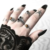 Hand with multiple sterling silver rings, 1 ring with a pair of black Onyx stones, other rings with genuine golden brown Tiger eye stones, light nature themed background