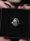 Drop shaped silver labradorite ring on black background