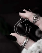 hand holding snake earrings, side view. also showing a pagan pentagram ring in sterling silver.