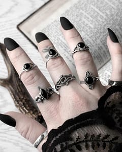 Hand with long black nails, occult finger tattoos, and many sterling silver rings, in the middle a duo snake ring
