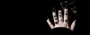 Gothic & Occult rings on hand with long black nails, a book in the background