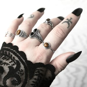 Hand with multiple sterling silver rings, 1 ring with a pair of black Onyx stones, other rings with genuine golden brown Tiger eye stones, light nature themed background