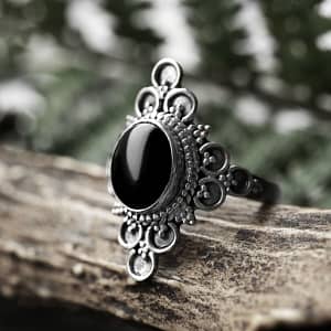 Ariana black stone ring in sterling silver on a brown branch, green background