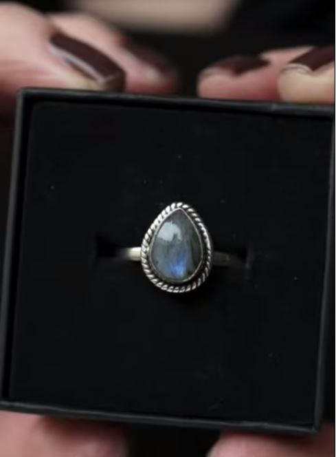 Drop shaped silver labradorite ring on black background