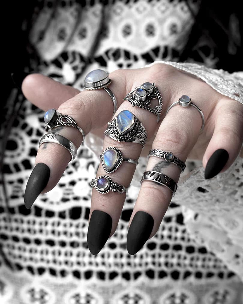 Magical selection of sterling silver moonstone rings on hand with black nails