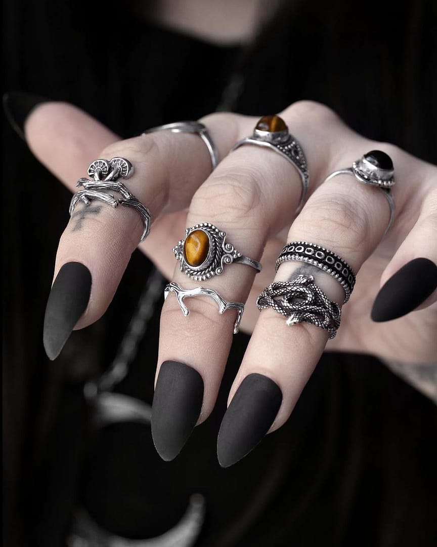 Sterling Silver rings with snake & mushrooms, Genuine Gemstones Tiger Eye Onyx Rings Hellaholics Close-up view of a hand with multiple sterling silver rings, 1 ring shaped like a branch with mushrooms, 1 ring with 2 entwined snakes, 1 ring with a genuine golden brown Tiger eye stone, dark background