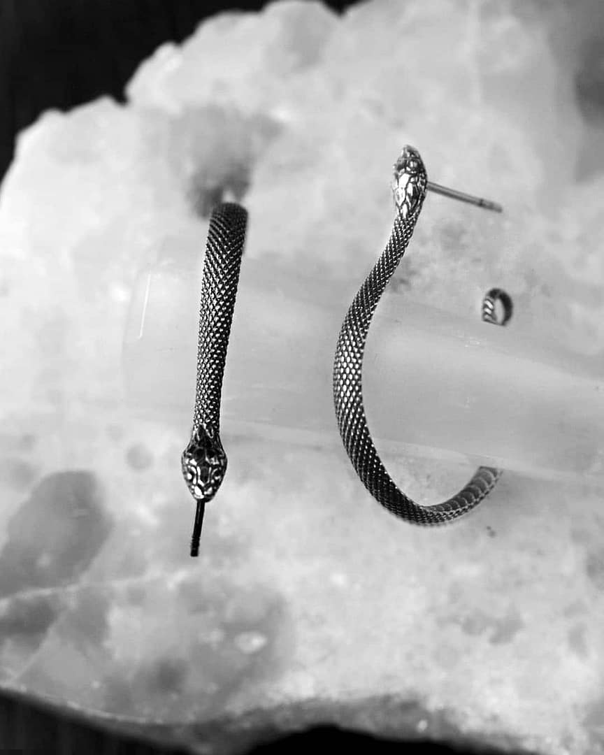serpent-snake-hoops-silver-earrings-close-up-hellaholics Sterling silver hoop snake earrings, with scales and intricate details. oxizided sterling silver. On white crystal background.