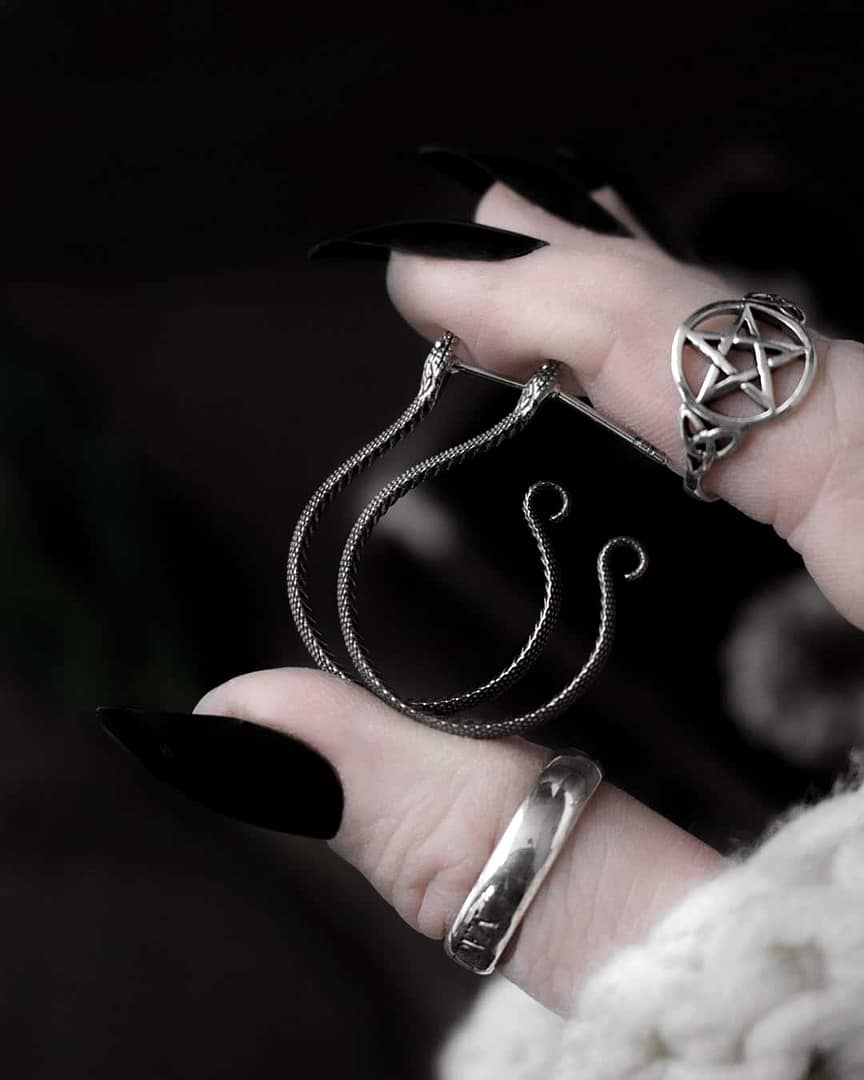 serpent-snake-hoops-silver-earrings-hellaholics hand holding snake earrings, side view. also showing a pagan pentagram ring in sterling silver.