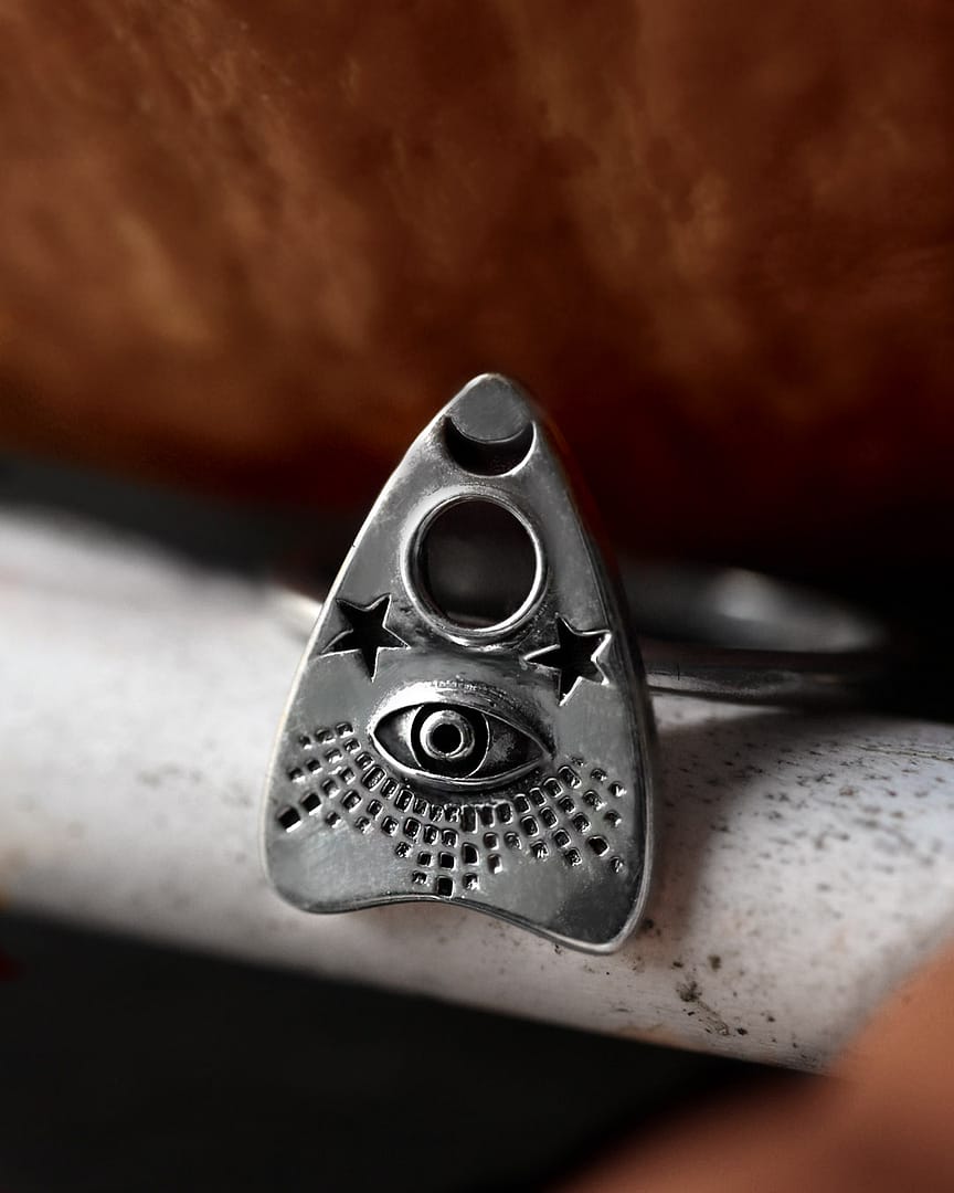 ouijah-silver-ring-close-up-hellaholics Recycled sterling silver Ouija Ring with a Spirit board detailed symbol, the ring sits on the edge of a light ceramic plate that holds a pumpkin