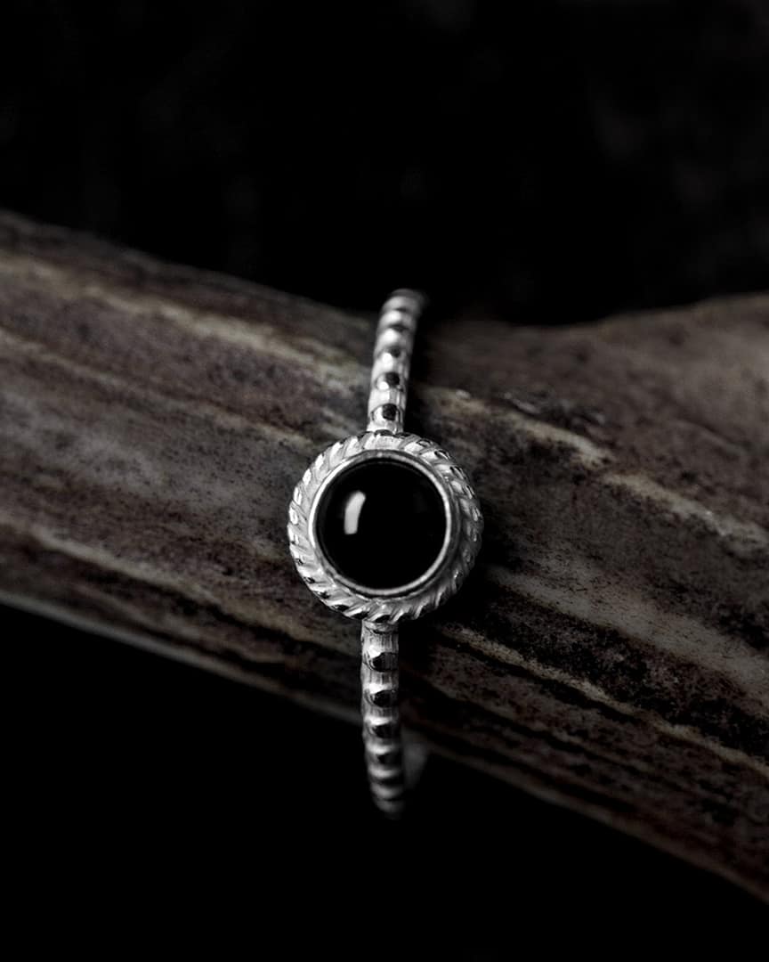 asteria-silver-onyx-stacking-ring-mood-dark-close-up-hellaholics Round petite black Onyx Stacking Ring in lightweight sterling silver on brown wooden branch and black background from Hellaholics